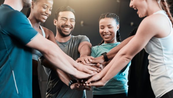 Shot of a group of friends with their hands stacked in motivation at the gym.